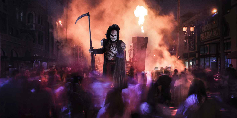 Close up portrait of man with a skull makeup standing infront of the halloween crowd.